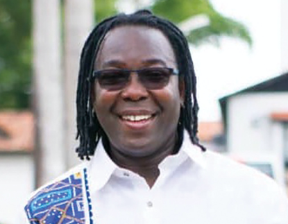Habib Iddrisu standing for a headshot with palm trees and a white building in the background