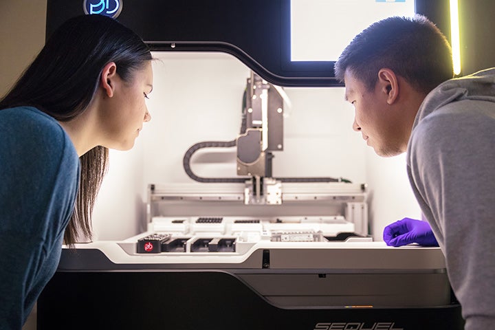 Students on each side of a scientific apparatus viewing samples