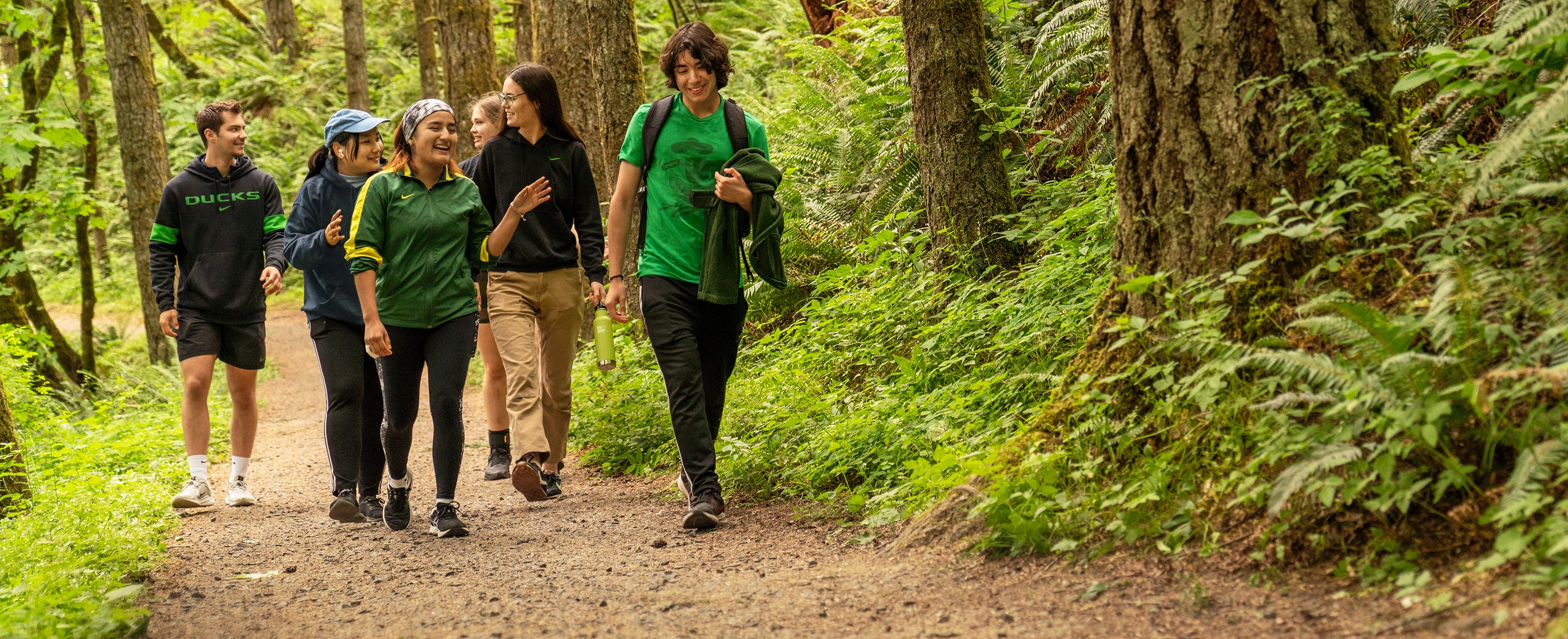 A group of students hiking on a dirt path through the forest.
