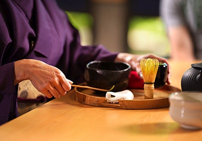 Close-up of a professor in a kimono mixing tea.