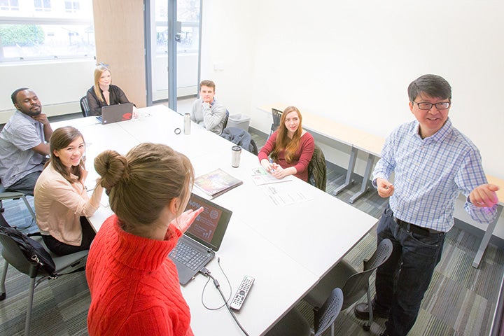 Professor and students of the Clark Honors College sitting and standing around a table