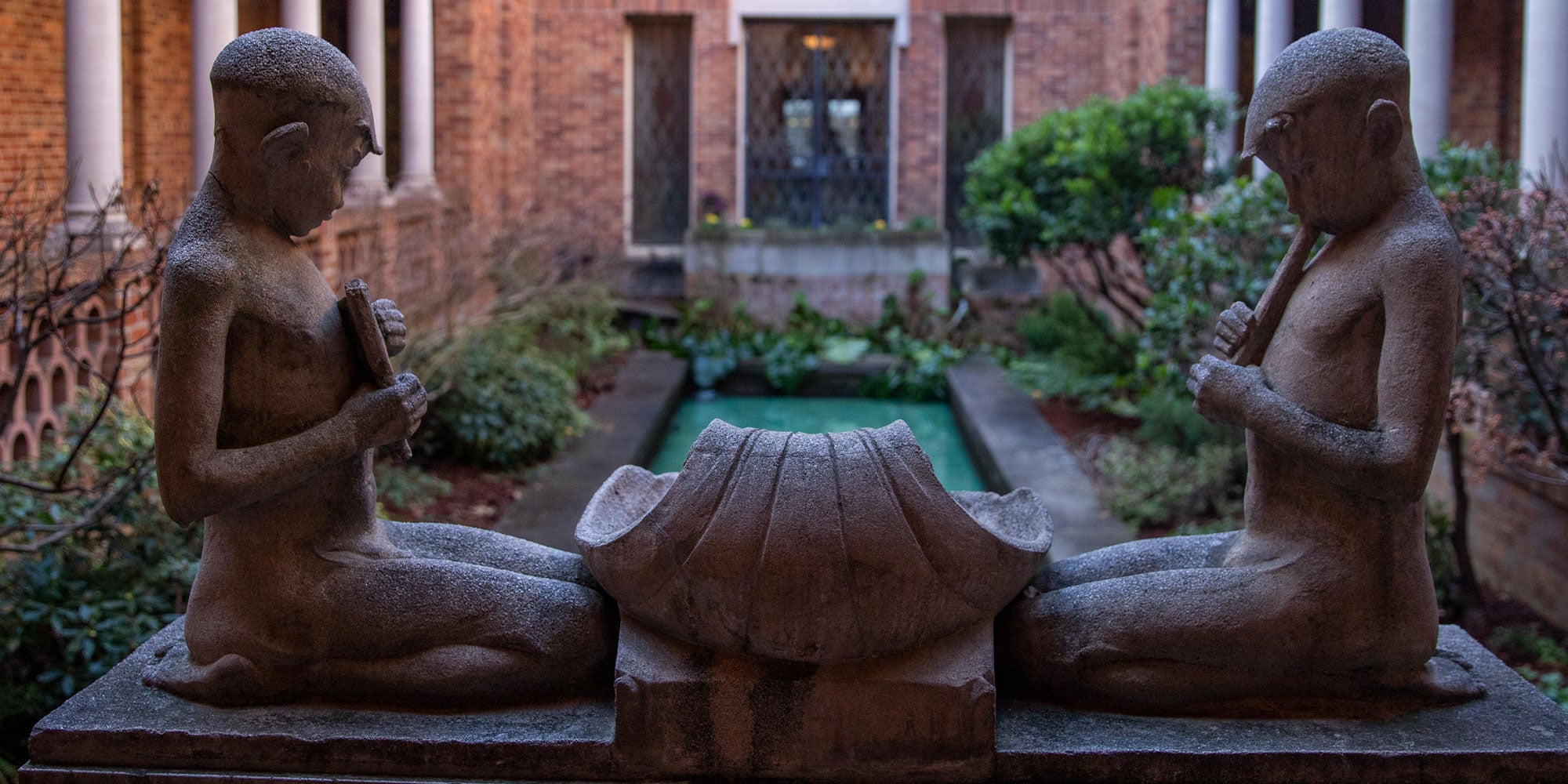 Sandstone statues of fawns playing flutes surrounded by a peaceful courtyard