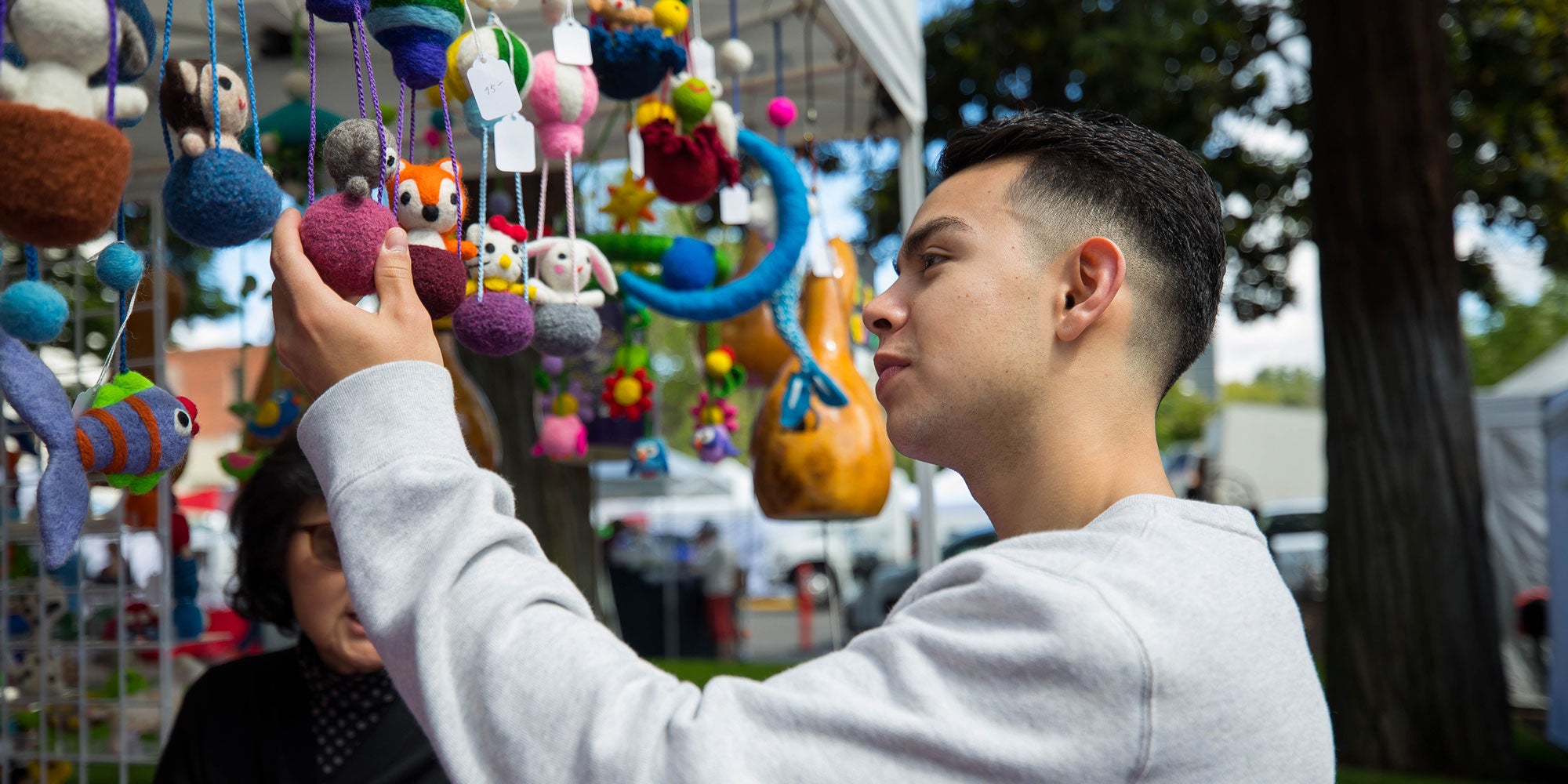 A student looking at felted figurines in a market stall